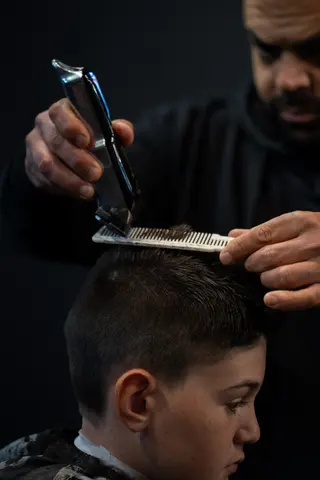 Close view of clippers and a comb shaping a haircut