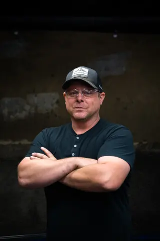 Portrait of a person with folded arms against a dark background