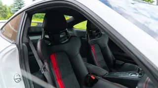Sports-car seats with red seatbelts viewed through an open door