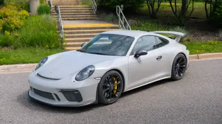 White sports car parked beside a tree-lined walkway