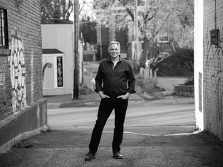 Black-and-white full-length portrait in a brick-lined alley