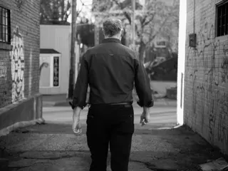 Black-and-white portrait of a person walking through an alley