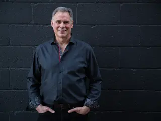 Portrait of a person facing the camera against a dark brick wall