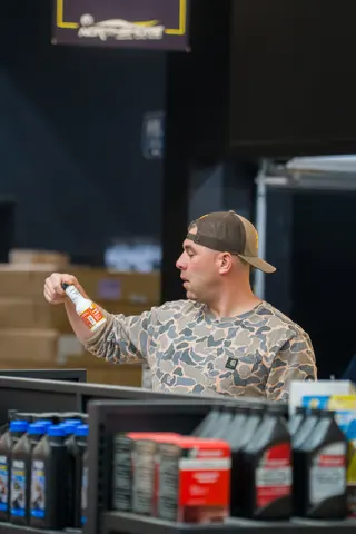 Person holding a drink bottle behind a shop counter