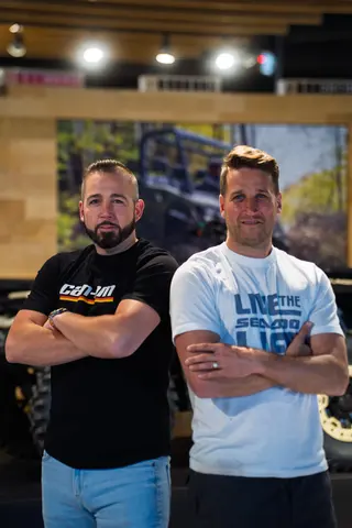 Two people posing with folded arms in a showroom