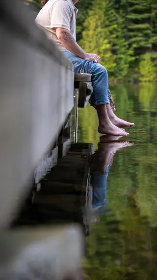 Bare feet hanging over the edge of a quiet lakeside dock