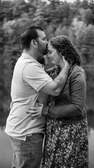 Black-and-white portrait of a couple embracing beside the water