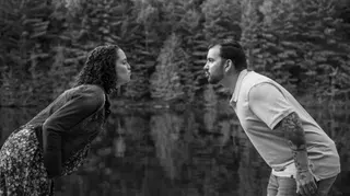 Couple leaning toward one another by the water in black and white