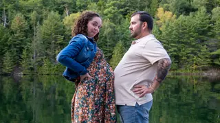Couple laughing with their hands on their hips beside a lake