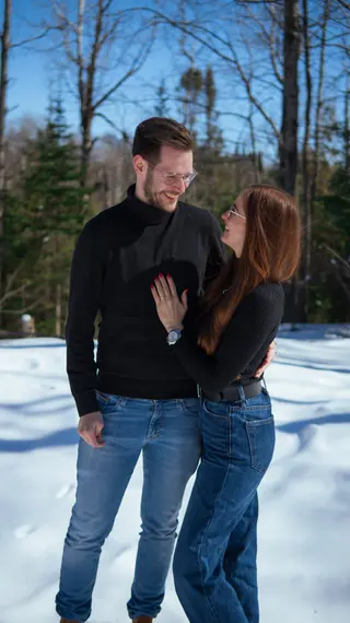 Couple embracing in matching dark tops in a snowy woodland