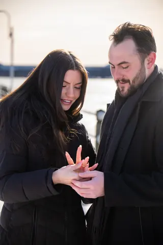Couple looking at an engagement ring on a snowy waterfront