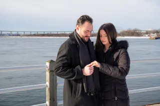 Couple looking at their hands beside the water in winter