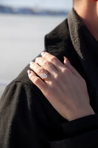 Close detail of an engagement ring against a dark winter coat