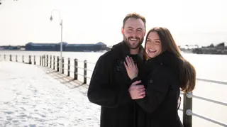 Smiling couple together on a snowy waterfront path