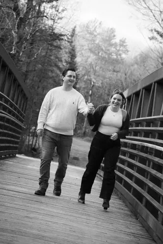 Black-and-white photograph of a couple walking on a bridge