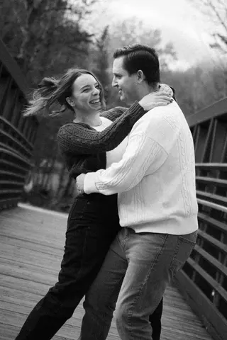 Black-and-white portrait of a couple dancing on a bridge