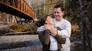 Couple embracing beneath a wooden bridge