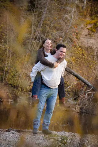 Couple laughing during a piggyback ride beside the water