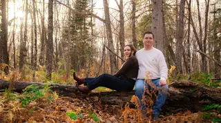 Couple sitting together on a fallen log in the woods