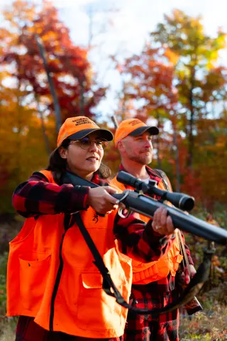 Couple posing with a long gun in orange safety vests