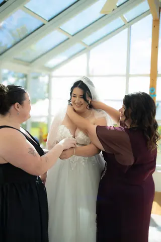 Bride getting ready with two attendants in a bright windowed room