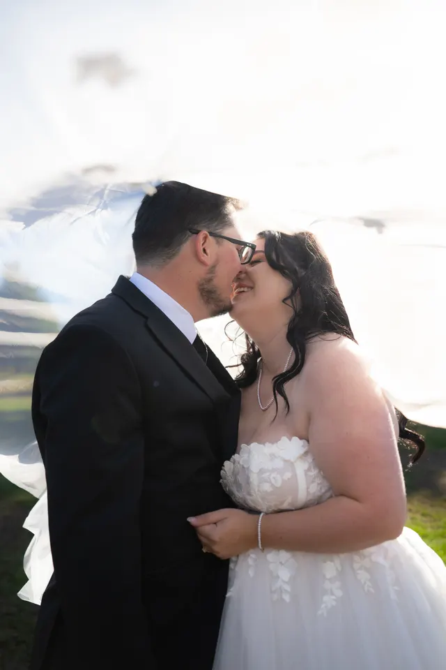 Close portrait of newlyweds beneath a sunlit veil