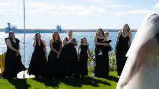 Bridal attendants seeing the bride for the first time beside the water