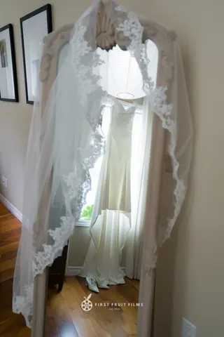 Wedding dress hanging beside an ornate mirror