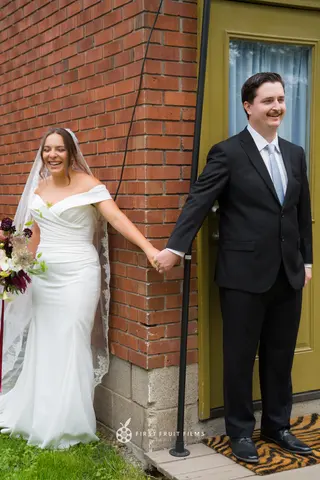 Bride and groom holding hands beside a brick doorway