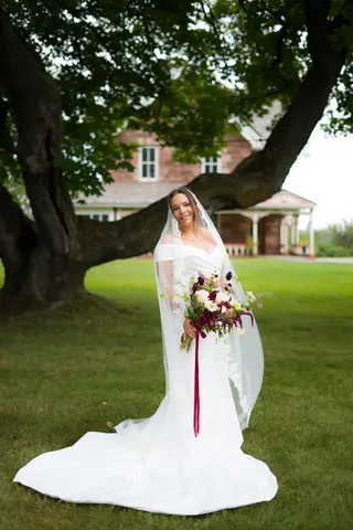 Bride and her bouquet beneath a broad tree