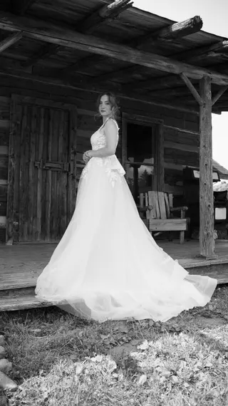 Black-and-white portrait of a bride beside a rustic wooden building