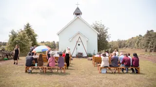 Outdoor wedding ceremony beside a small white chapel