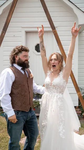 Bride raising both hands in celebration beside the groom