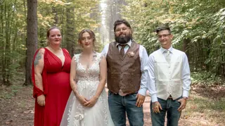 Newlyweds posing with two guests on a wooded path