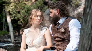 Bride and groom sitting together beside a tree
