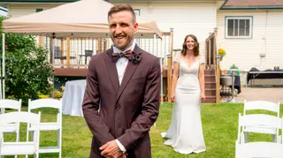 Groom waiting while the bride approaches across the lawn
