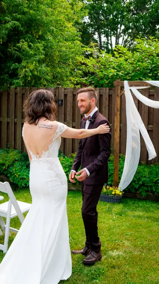 Bride reaching toward the groom during their first look