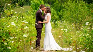 Newlyweds kissing in a sunlit clearing