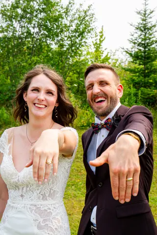 Smiling newlyweds showing their wedding rings to the camera
