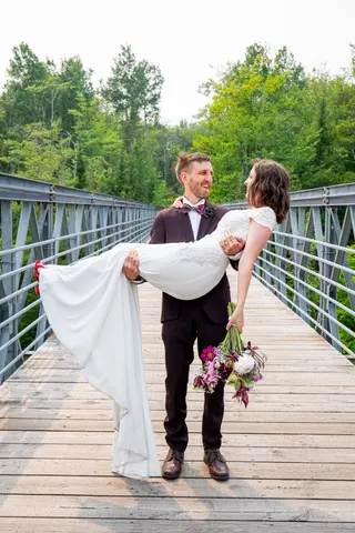 Groom carrying the bride on a wooden footbridge