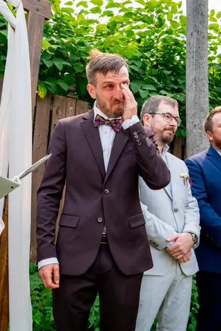Groom wiping his eye during an outdoor ceremony