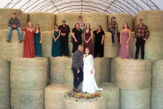 Wedding group arranged around stacked hay bales
