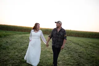 Bride and groom holding hands beside a field at sunset
