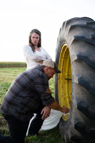 Bride and groom posing beside a large tractor tire