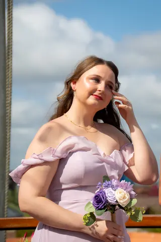 Bridesmaid holding a purple bouquet beside the water
