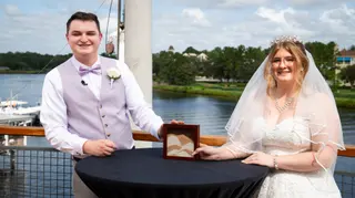 Newlyweds standing beside a ceremony table on a waterfront deck
