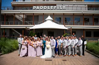 Wedding party gathered in front of a riverboat-style venue
