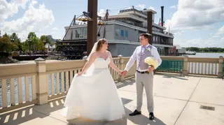 Bride and groom holding hands on a sunny waterfront terrace