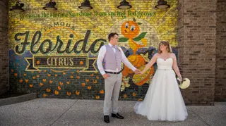 Newlyweds posing in front of a colourful citrus mural