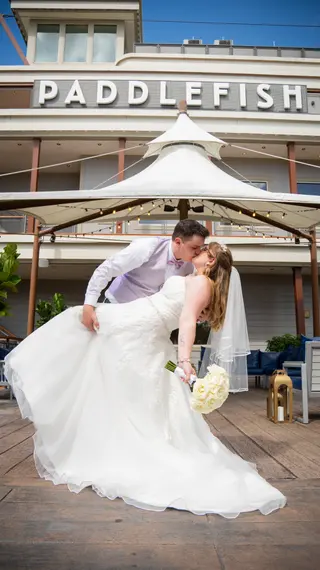 Groom dipping the bride in front of a riverboat-style building